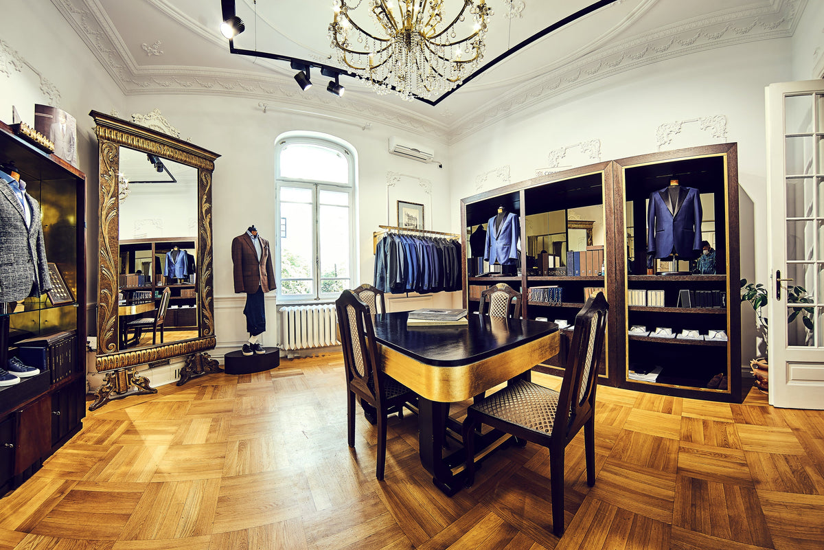 Masă de consultanță din lemn, înconjurată de costume expuse în showroomul Consiglieri