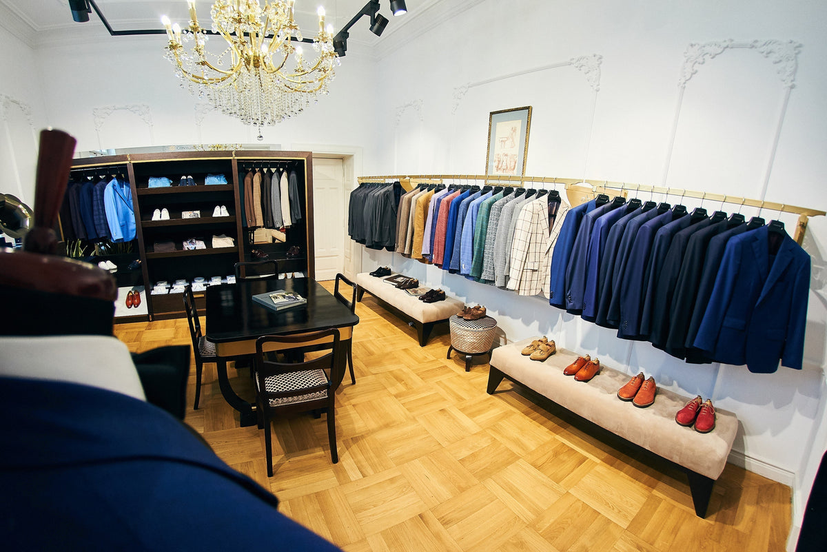 Sacouri în nuanțe de bleumarin, gri și bej, alături de cămăși și pantofi în showroomul Consiglieri