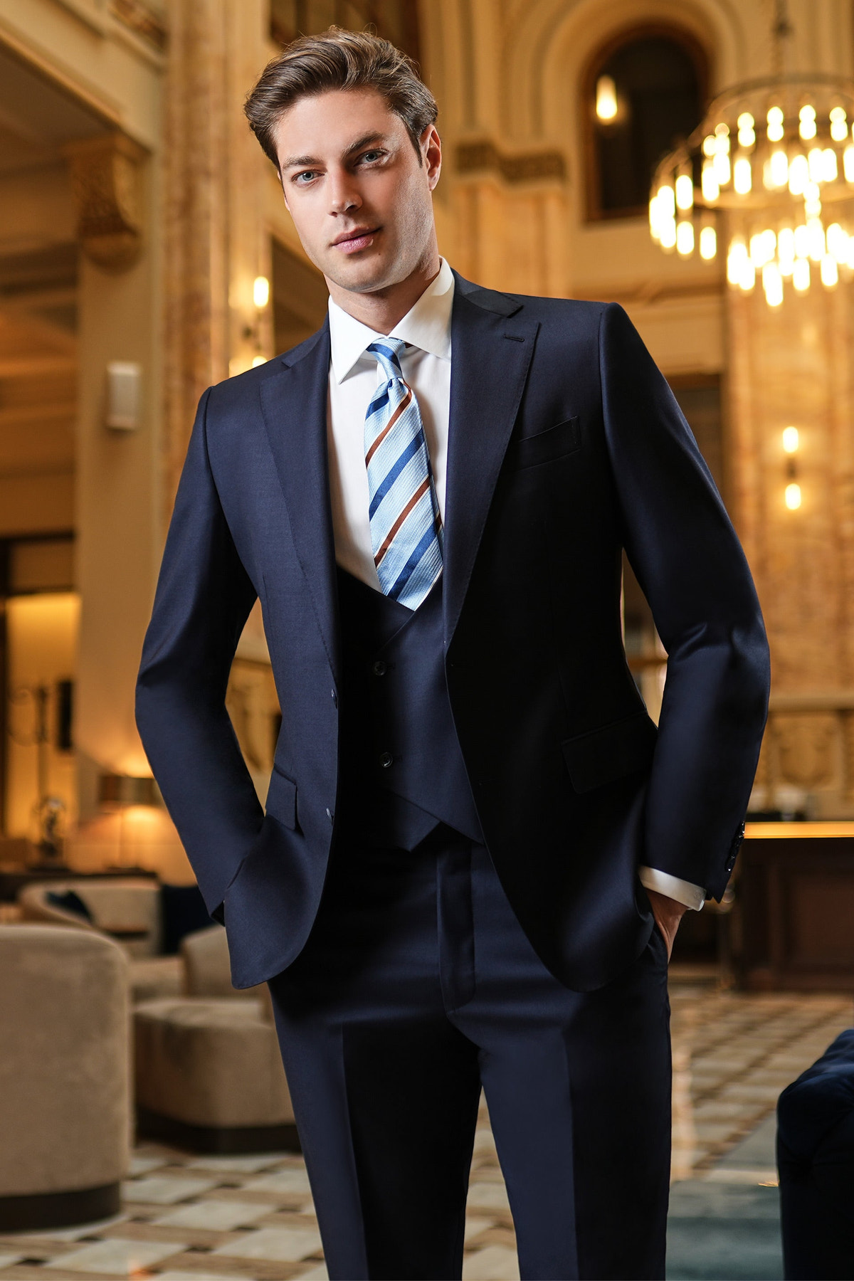 Costum bleumarin cu vestă și cravată în dungi, într-un interior elegant