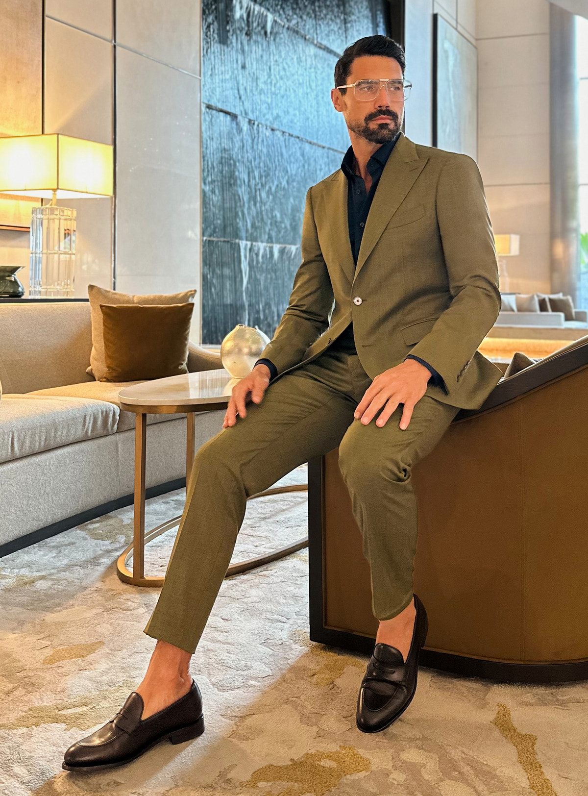 Costum verde măsliniu Consiglieri, într-o ținută relaxată, așezată în salon