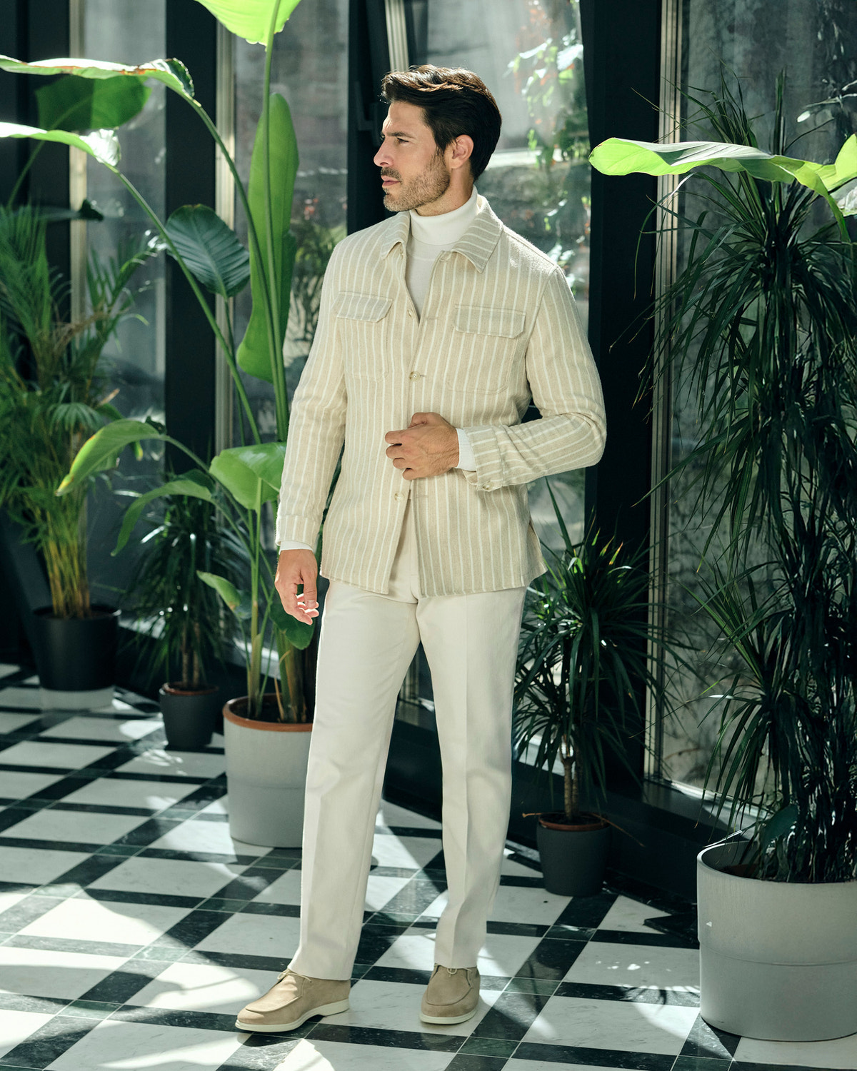 Jachetă crem Consiglieri cu dungi fine, purtată cu maletă și pantaloni crem