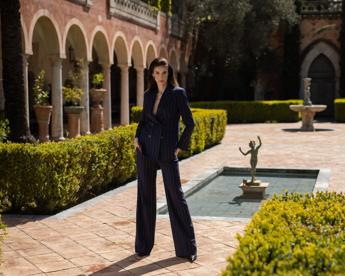 Costum feminin bleumarin cu pantaloni largi, lângă o fântână