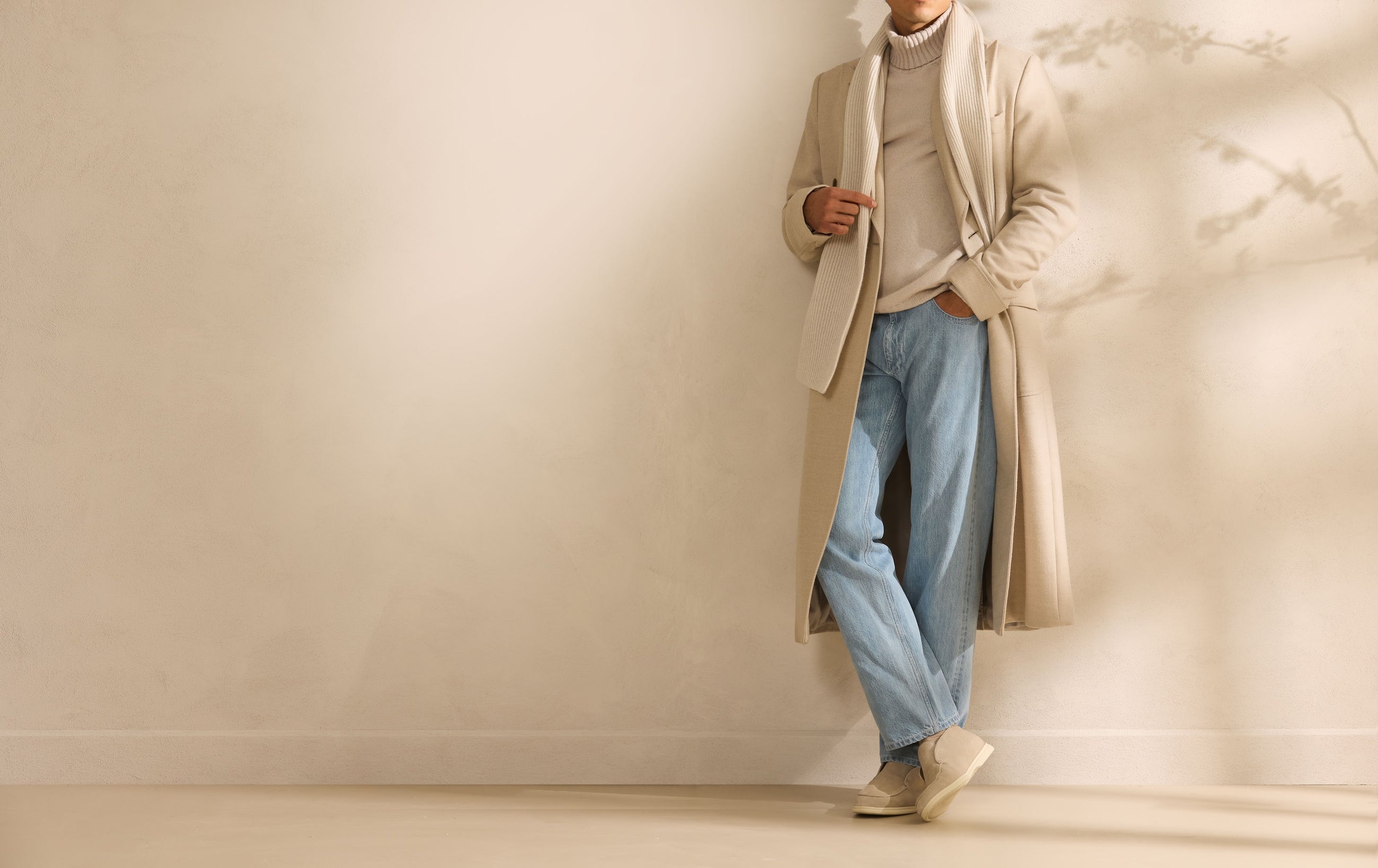 Overcoat deschis la culoare, purtat cu denim — formal și casual în același cadru.