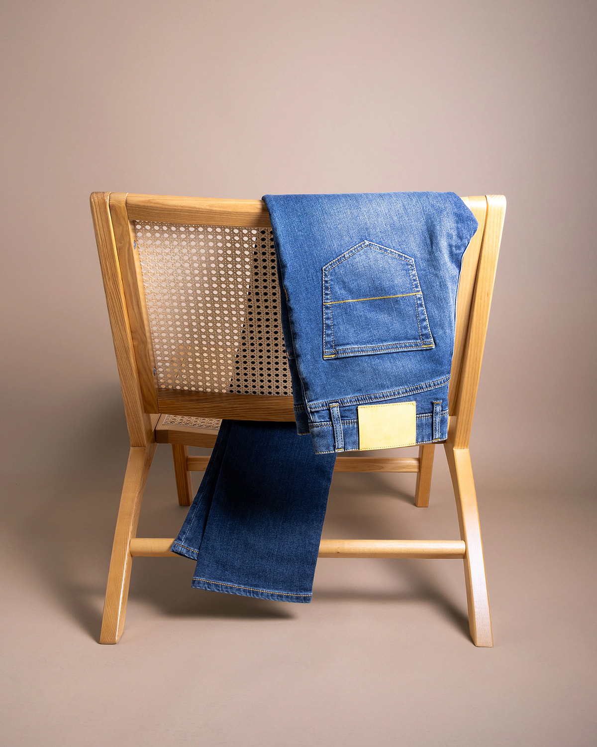 Denim albastru luminos, buzunar cu cusături aurii și etichetă deschisă.
