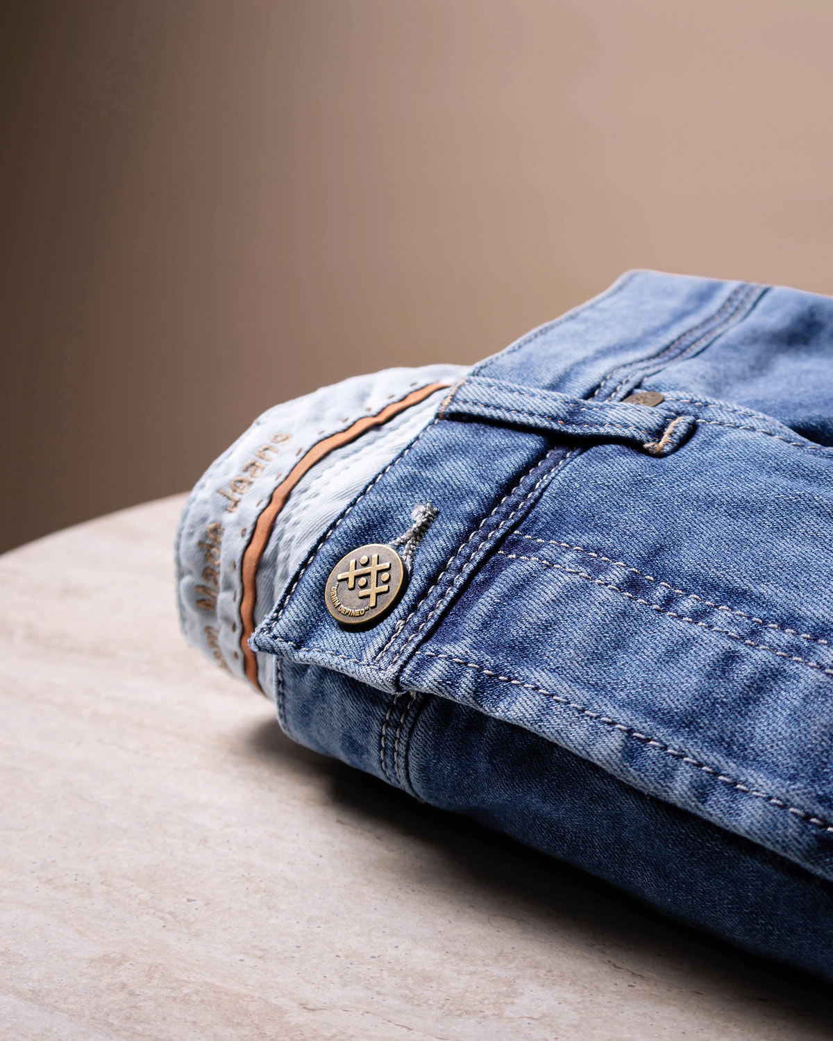 Denim albastru prespălat, nasture metalic și cusături argintii.