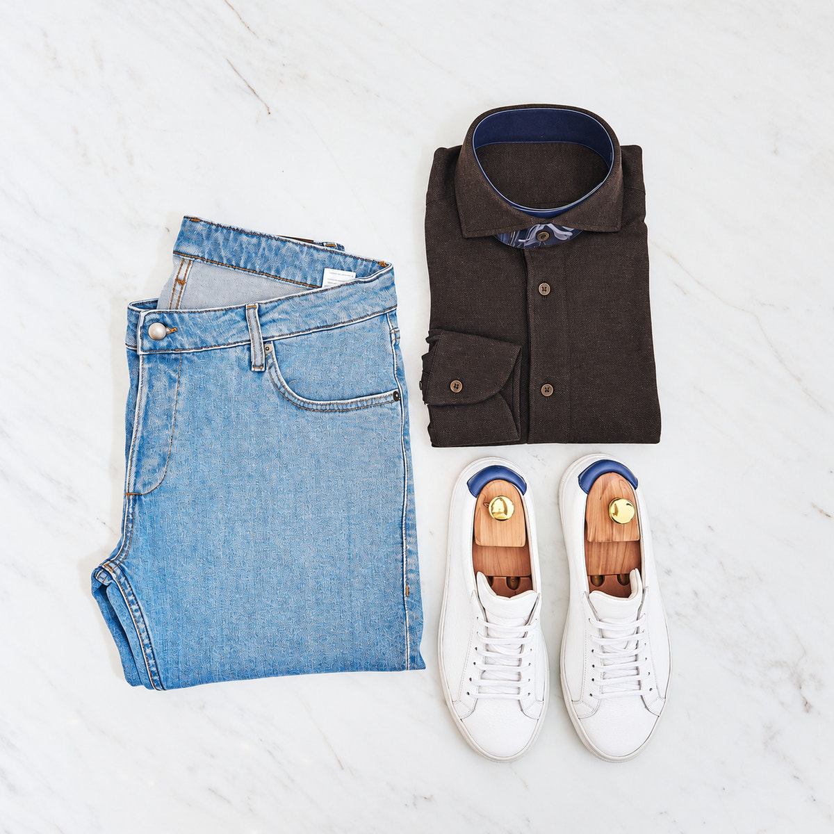 Jeans albaștri, cămașă închisă și sneakers albi Consiglieri, într-o compoziție de ținută