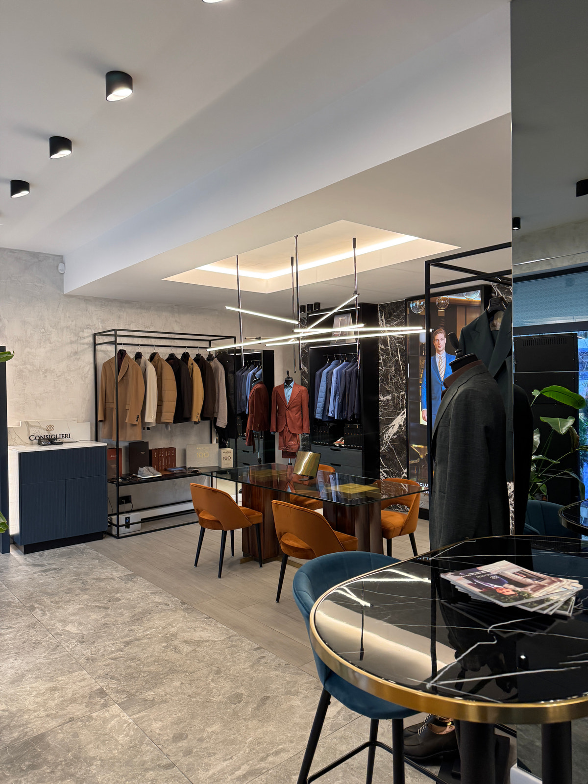 Colț al showroomului, cu scaun albastru și selecții de sacouri în fundal.