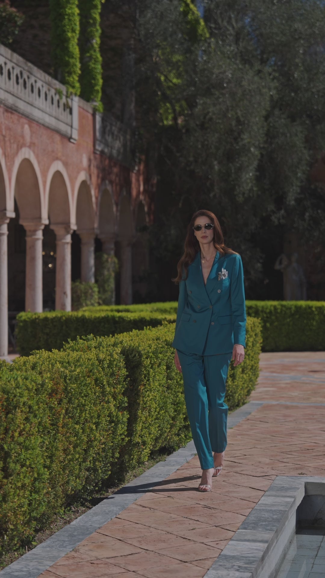 Costum feminin albastru-verzui Amalfi Consiglieri, pe o alee mărginită de gard viu