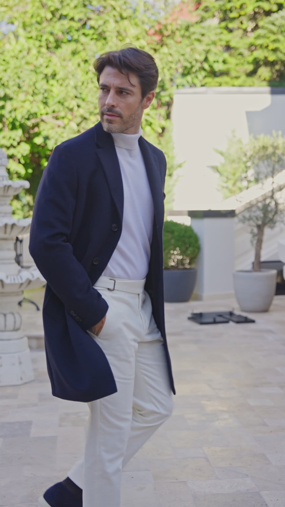 Palton bleumarin cu pantaloni albi, surprins într-o curte însorită