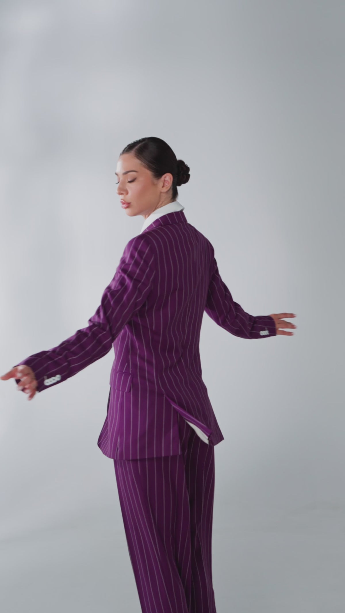 Costum feminin violet în dungi fine, surprins în mișcare