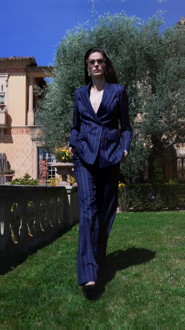 Costum feminin bleumarin, purtat cu ochelari de soare într-o grădină însorită
