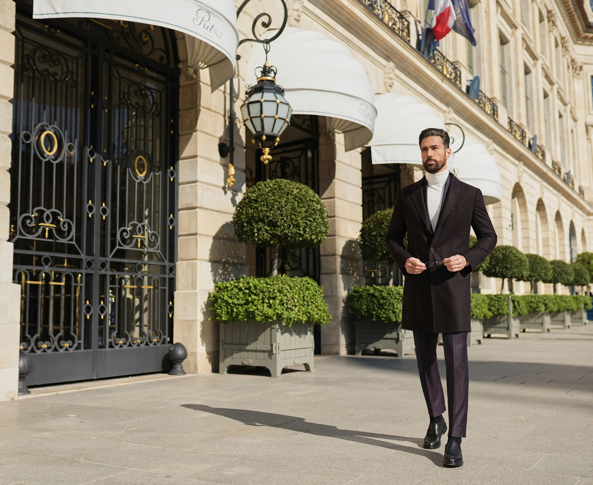 Palton St Moritz Consiglieri închis la culoare, cu maletă albă și pantaloni în tonuri apropiate